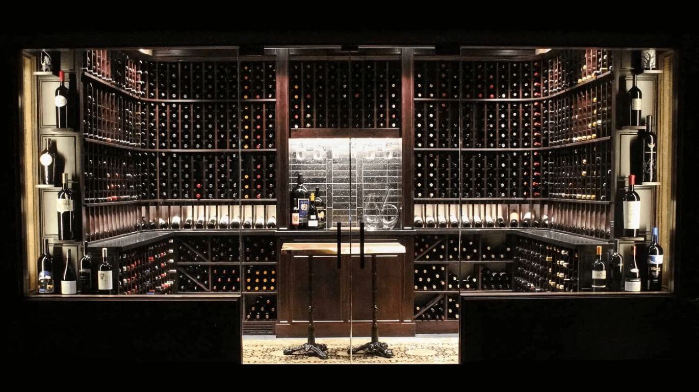 traditional wine cellar design with glass door and wooden racks by Genuwine Cellars