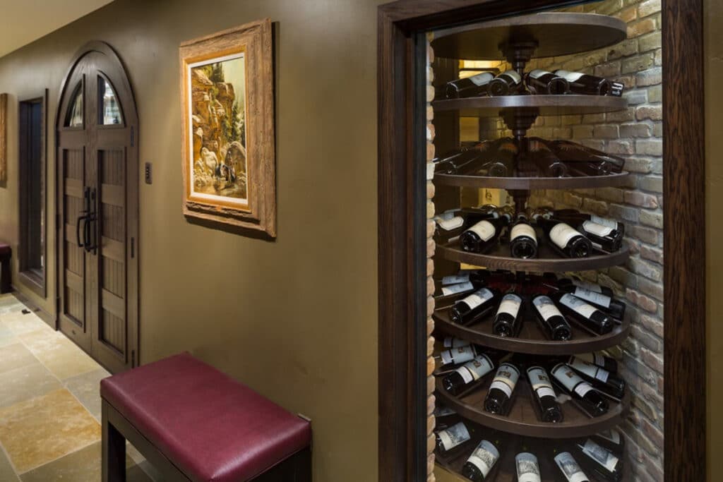 Jackson Hole Traditional Wine Cellar - arched door, wooden racks and stone walls