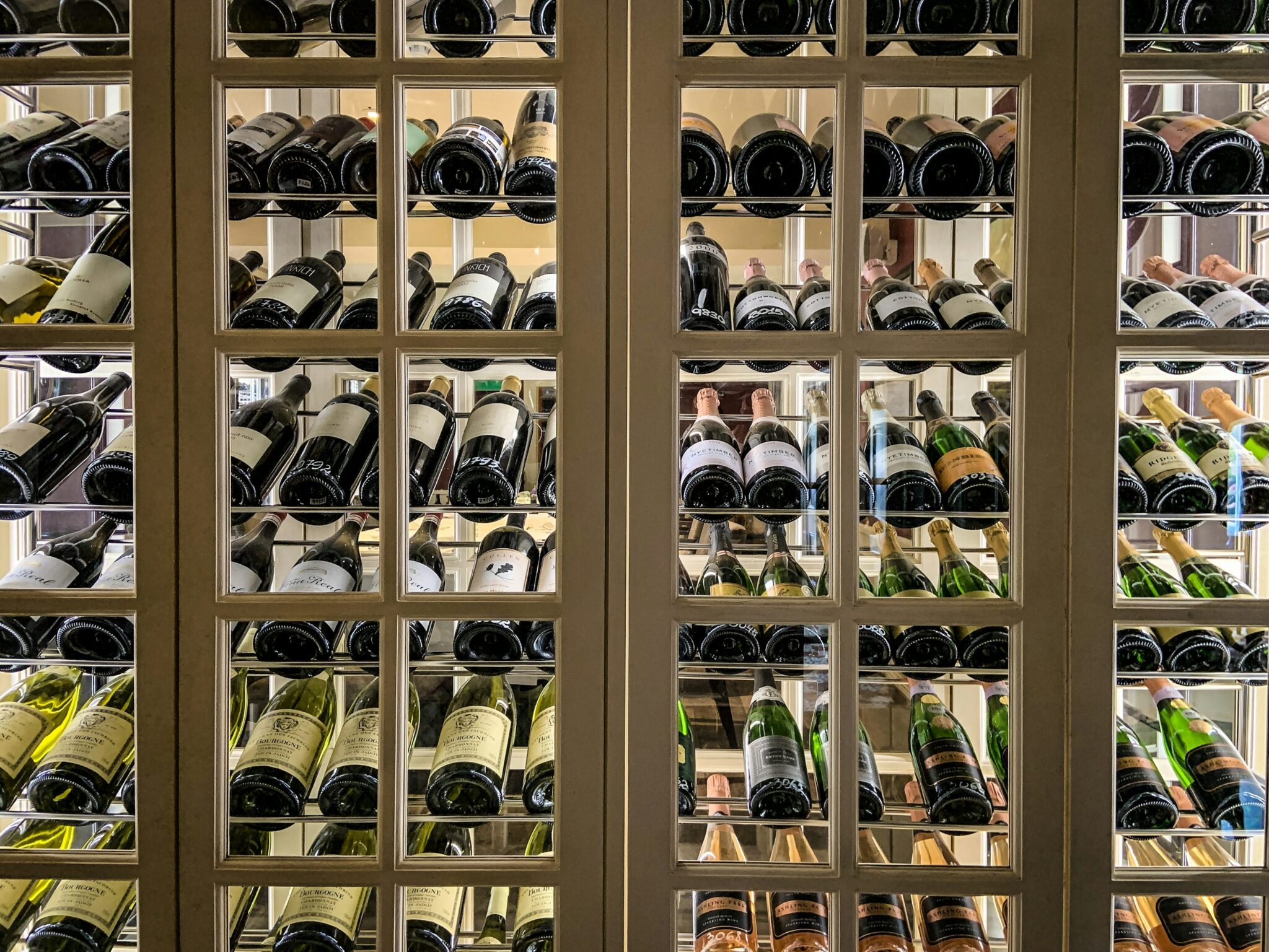 Custom wooden wine cellar with glass-front wine storage racks and bottle display