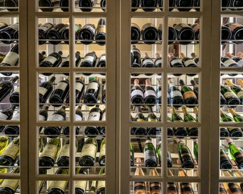 Custom wooden wine cellar with glass-front wine storage racks and bottle display